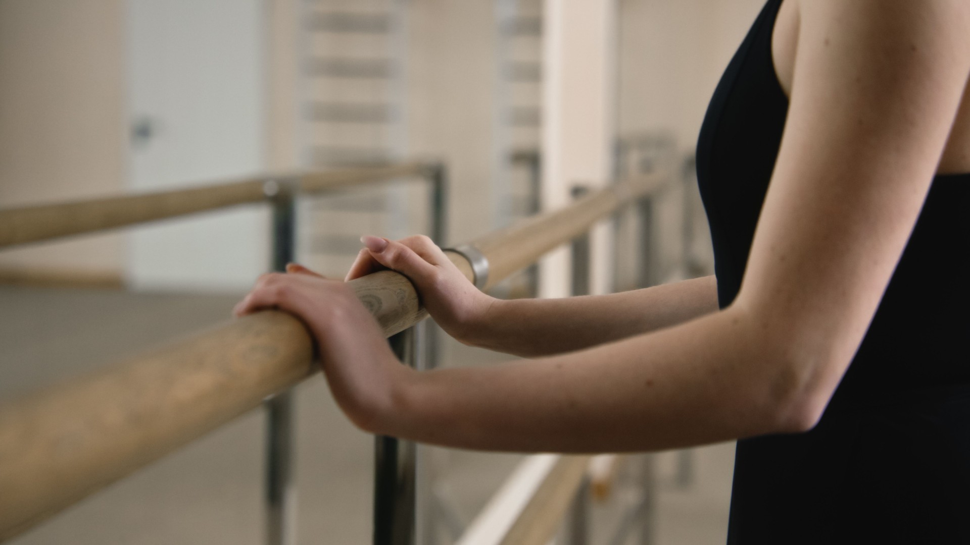 Female ballet dancer stands near ballet barre