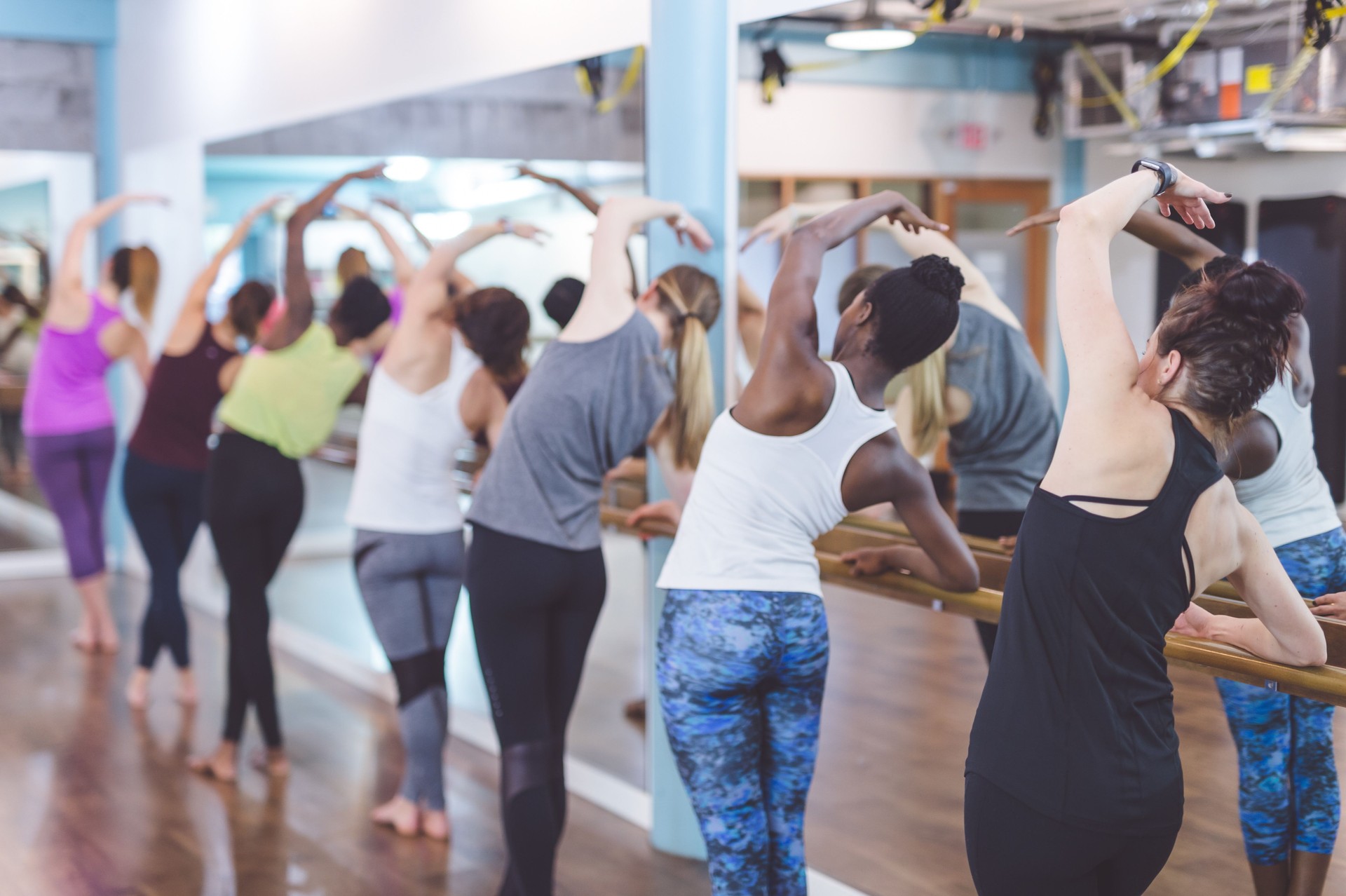 Multiethnic group of women do a barre workout together in a modern health club